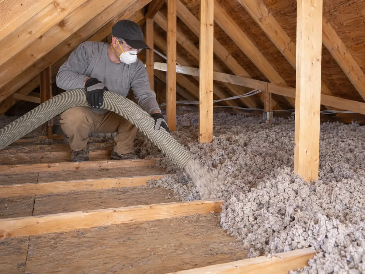 Technician removing existing loose-fill insulation from a residential attic floor